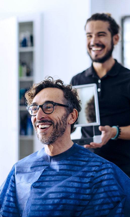 A smiling hairdresser shows haircut to client.