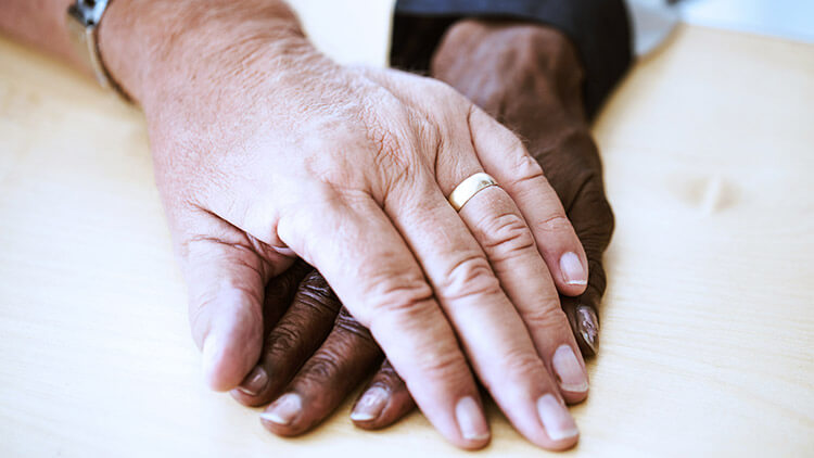 aged couple hands with wedding bands 