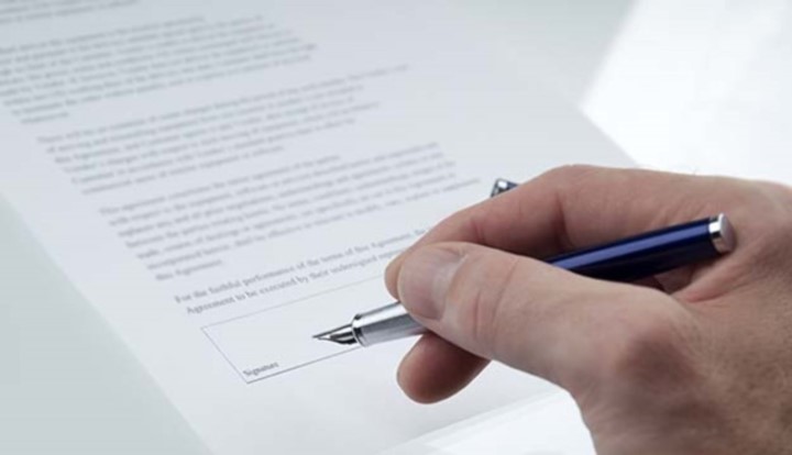 Person holding fountain pen about to sign document