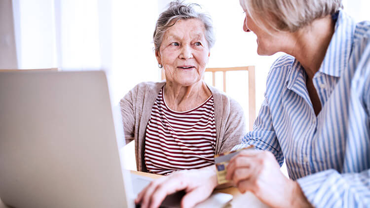 elderly woman and daughter helps on computer 