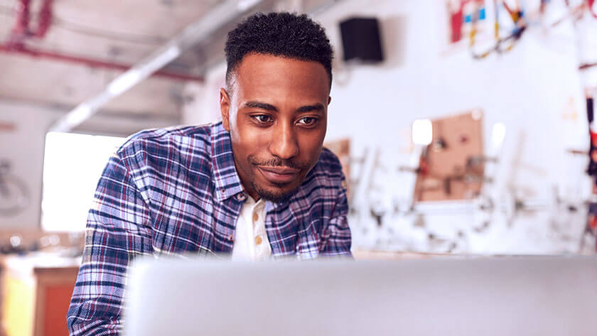 man-using-laptop-working-in-studio wearing checkered shirt 