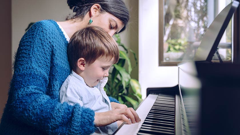 Mother holding child on lap playing piano