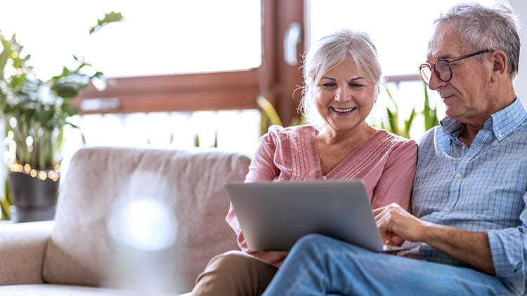 Senior woman and man look at laptop smiling