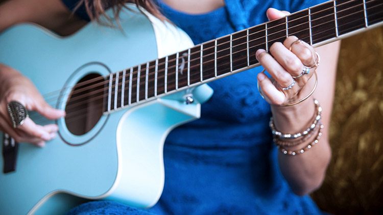 Woman wearing blue dress plays blue guitar