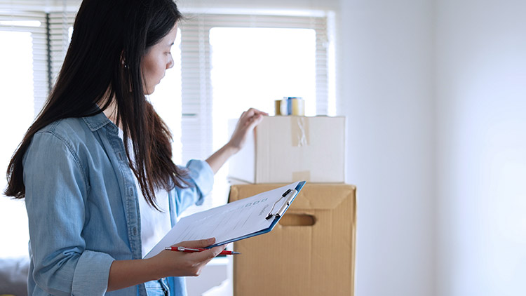 Woman holding clipboard looking at boxes