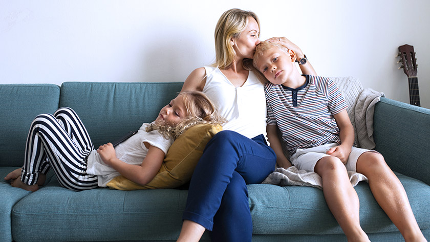 mother-sits-on-sofa-holding-kids