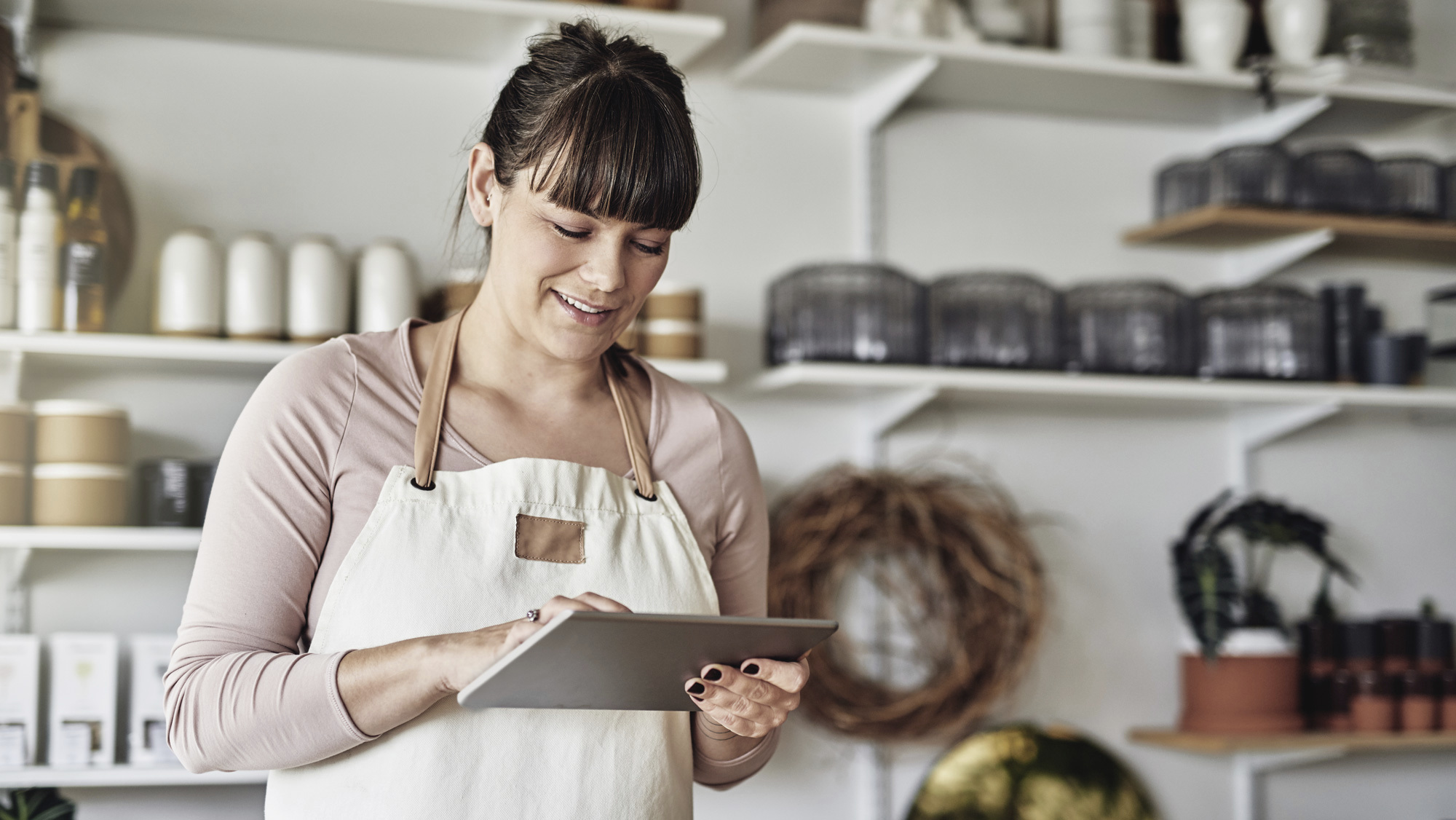 woman in apron looking at tablet 