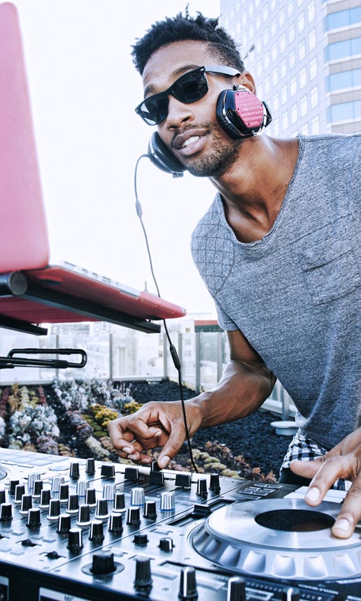 A business owner standing in front of turntables and DJing at an outdoor event.