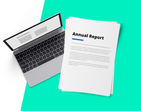 Next to a laptop, a document with the words annual report printed on it.