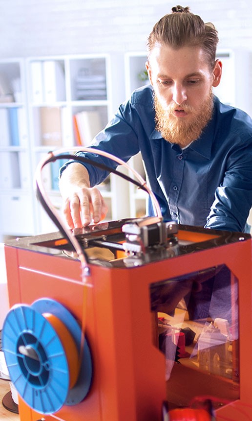 A bearded man works on his invention in a studio.