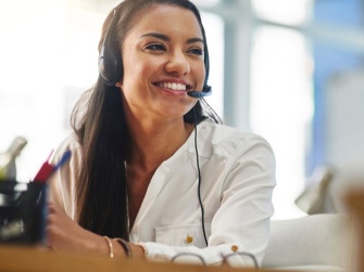 Woman in customer care on phone headset smiling.