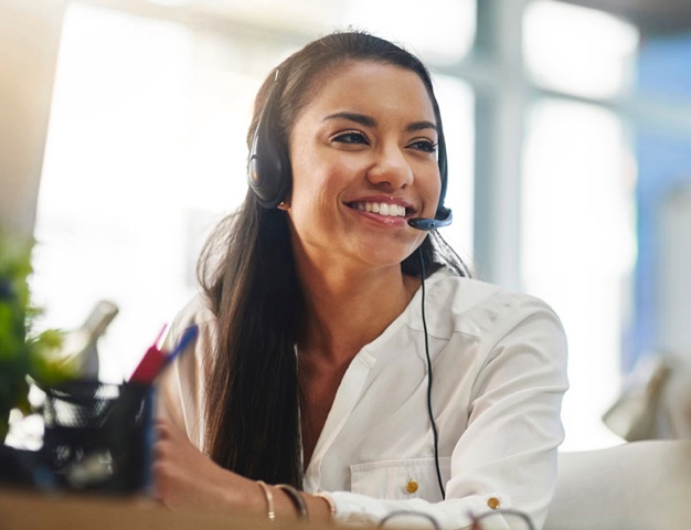 Woman in customer care on phone headset smiling.