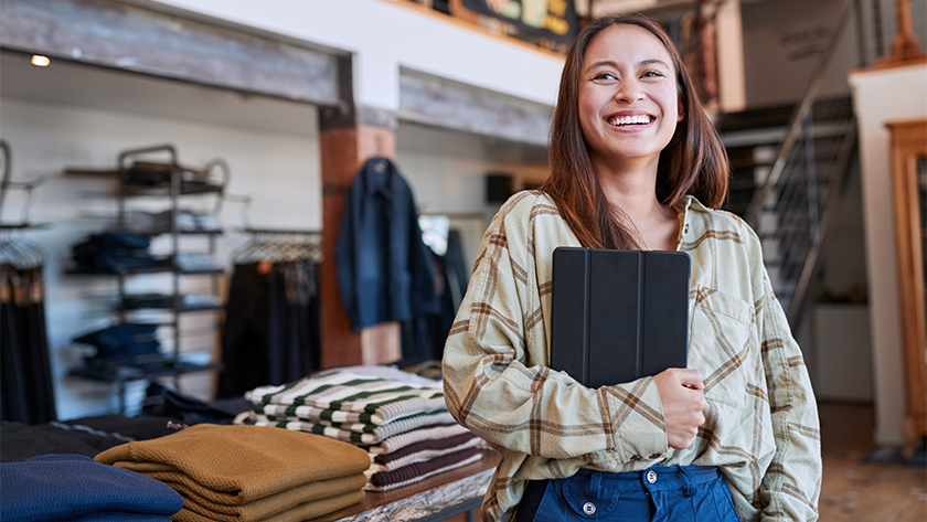 woman in retail store smiling holding a tablet