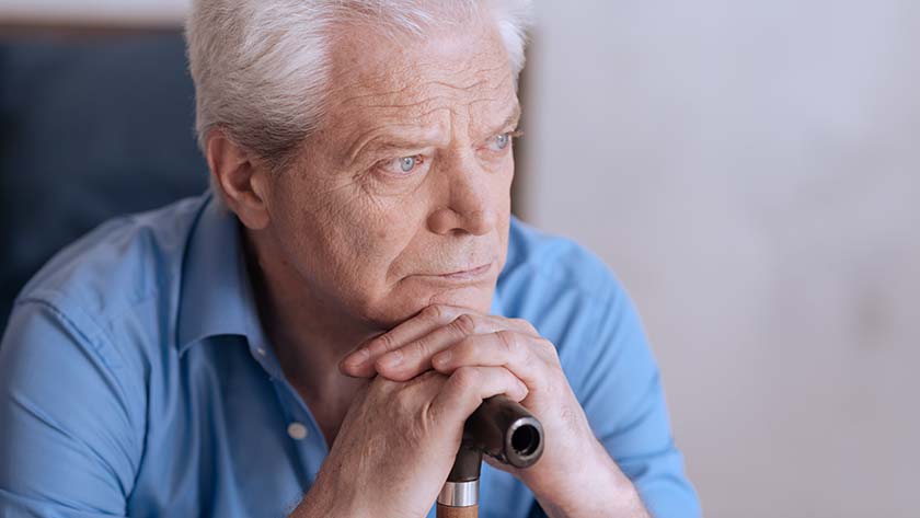 elderly man rest chin on cane 