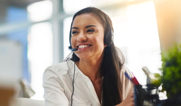 A smiling customer service agent talks on her headset.