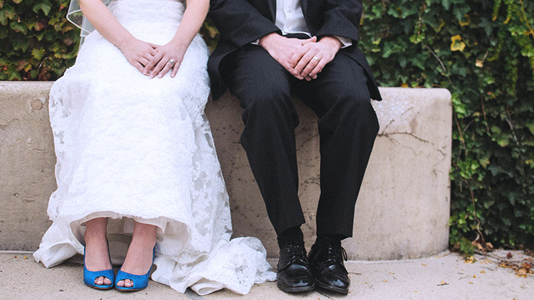 Bride and groom sit side by side in wedding clothes