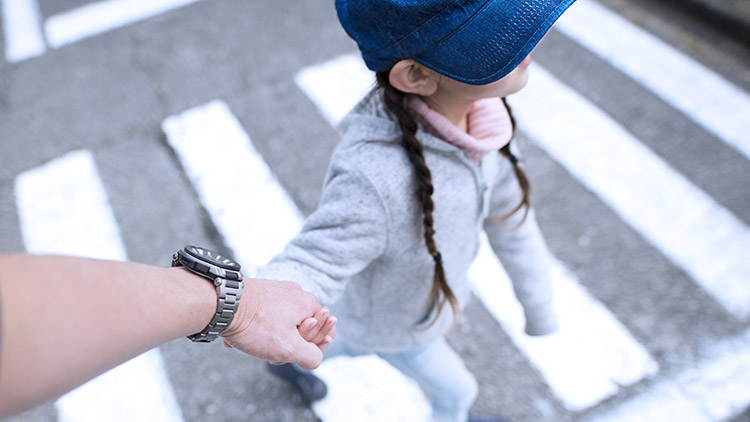 Father holding hand crossing street