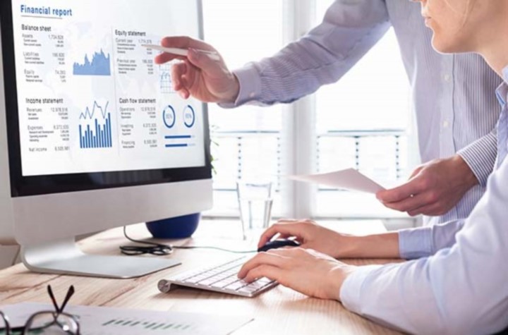 Businesspeople looking at financial reports on a computer screen