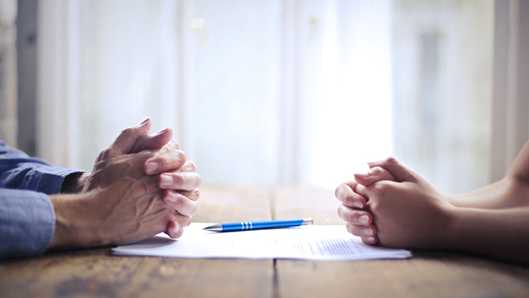 Man and woman face each other hands closed on table