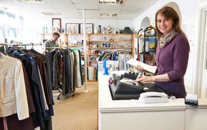 Employee at cash register smiling in a small clothing store