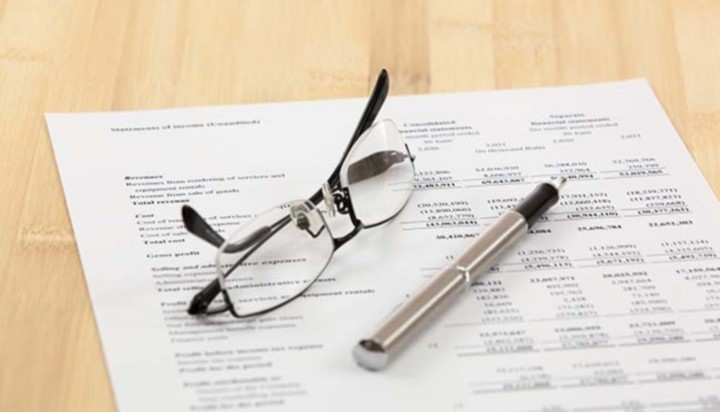 Glasses and pen sitting on profit and loss sheet