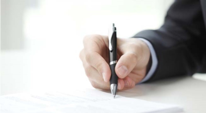 Hand holding a pen writing on a piece of paper