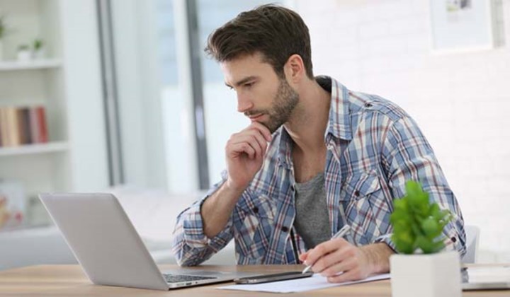 Man in plaid shirt looking intently at his laptop