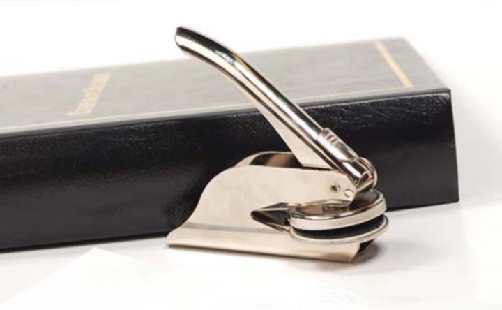 Metal stamping tool next to leather binder