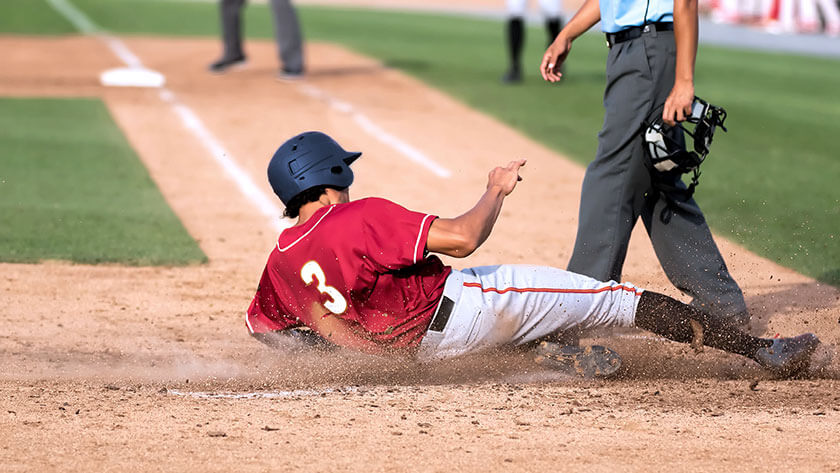 baseball player sliding into base with umpire 