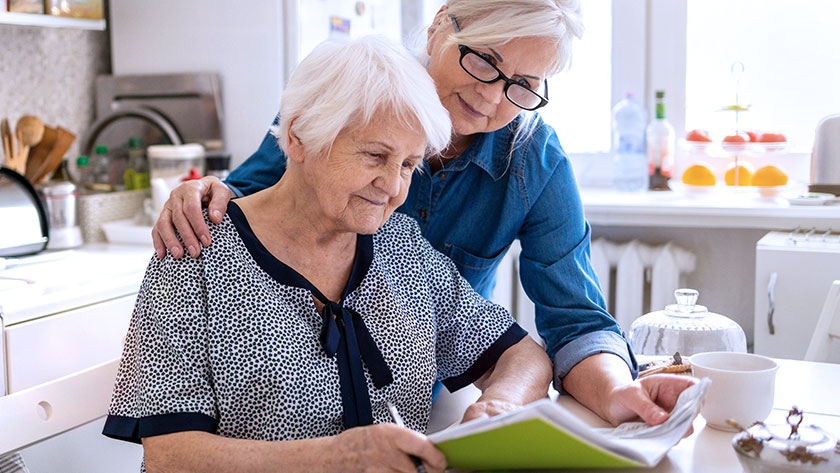 Elderly mother and adult daughter look over documents