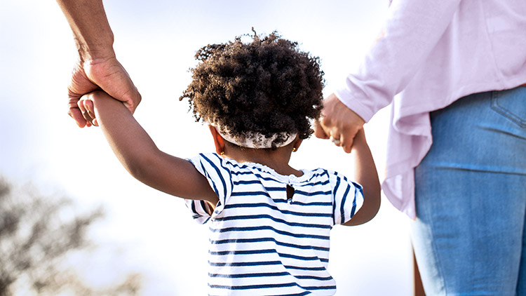 Father and mother hold toddlers hands