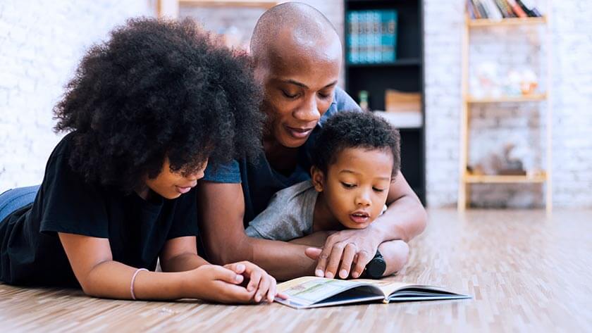 father-reading-to-kids-on-floor wearing blue shirt 