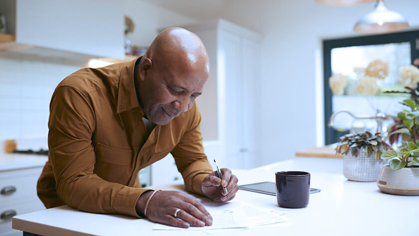 man-filling-out-estate-planning-forms at kitchen counter 