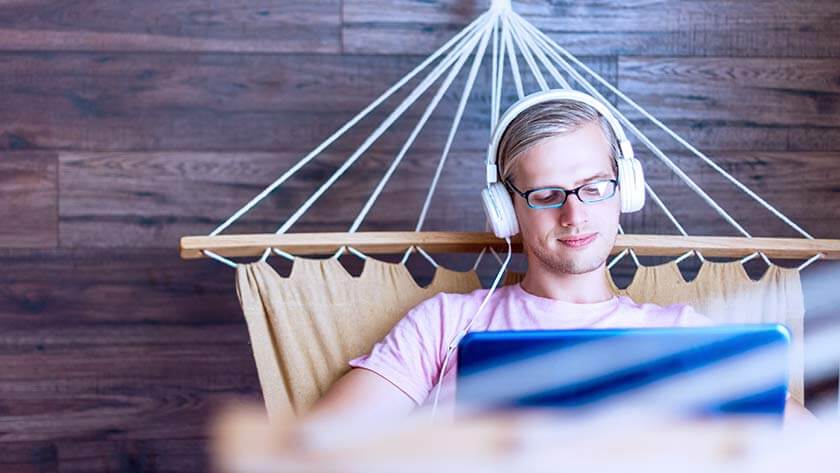 man-wearing-glasses-and-headphones-works-in-blue hammock