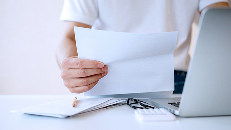 man-holding-mail-looking-at-laptop