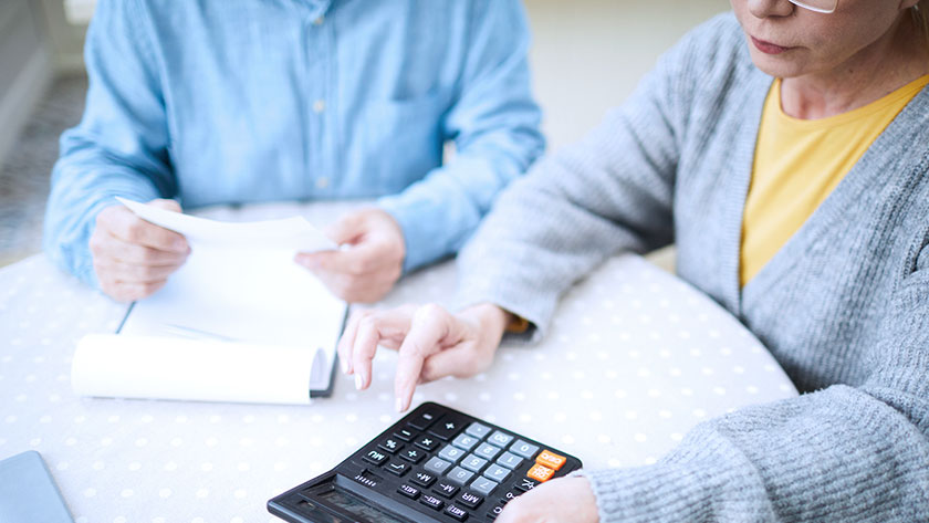 Senior couple using calculator at table