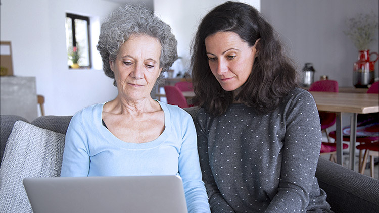 Senior mother and adult daughter look at computer
