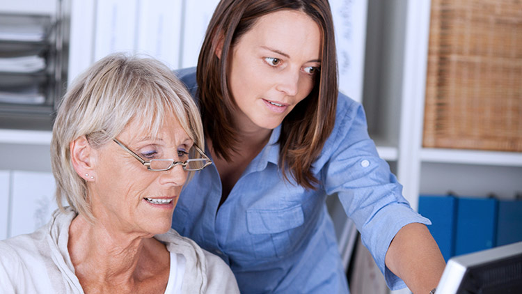 Senior mother and adult daughter look at computer