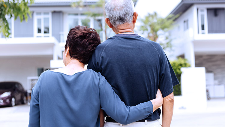 Senior woman hugs husband and looks at house