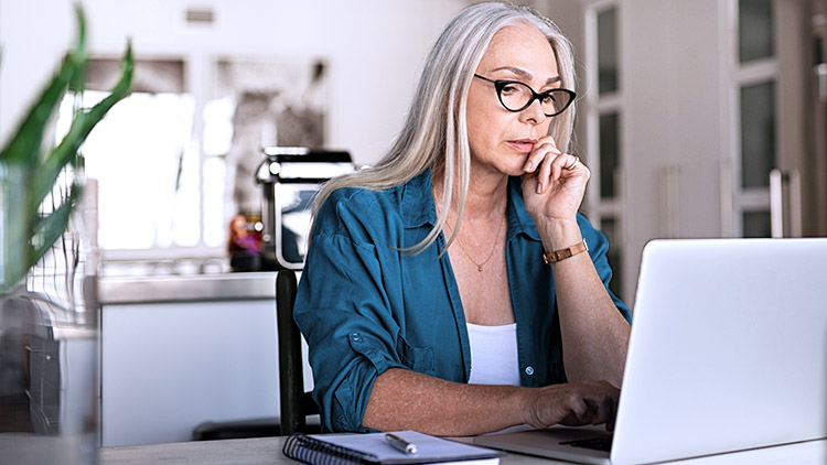 Senior woman looks at laptop