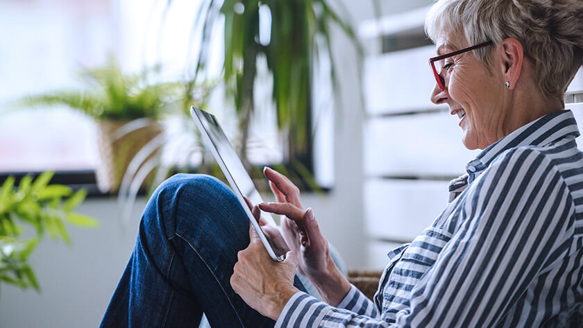 senior woman using ipad sitting on the sofa 