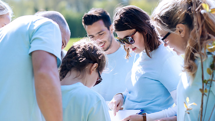 Volunteers gather around woman with clipboard