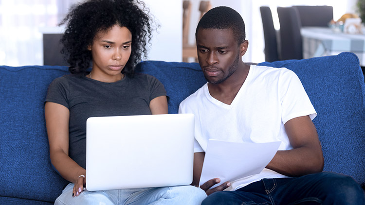 Woman and man sitting on sofa looking at laptop