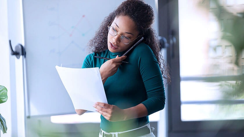 woman-on-phone-looking-over-documents wearing green shirt