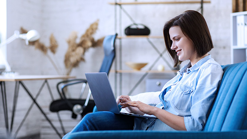 Woman sitting on sofa typing on laptop