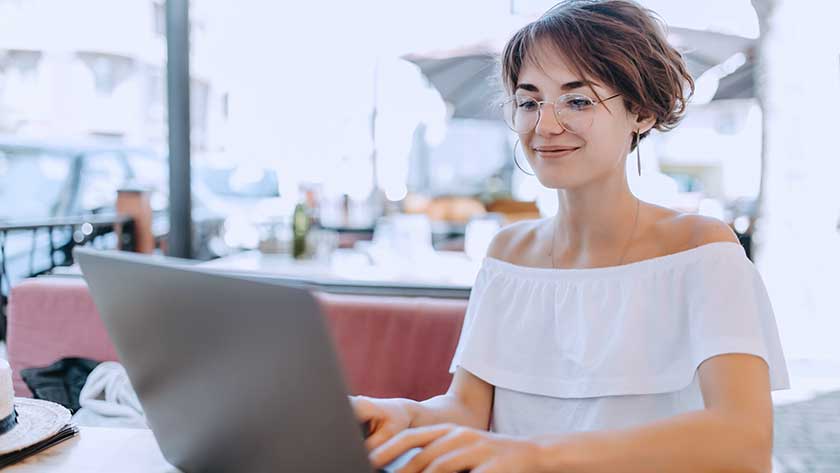 woman-smiling-using-laptop-outdoor-cafe