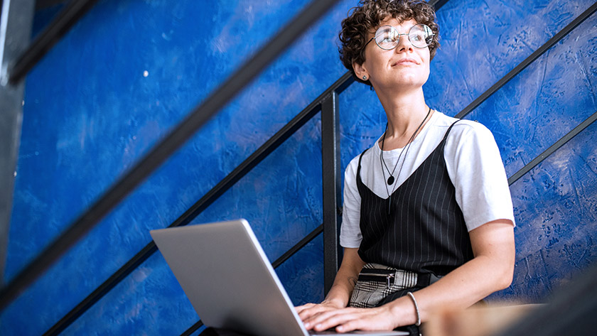 Woman holding laptop and looking out window