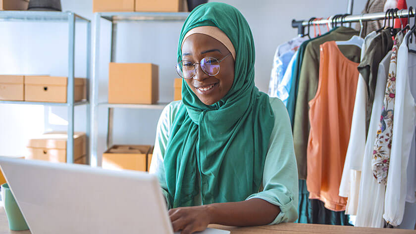 woman-wearing-headscarf-fashion-designer-uses-laptop in her studio