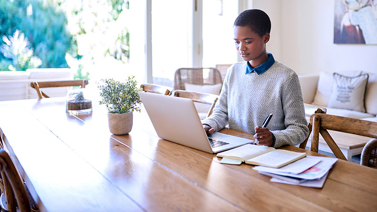 Woman working on laptop at home table