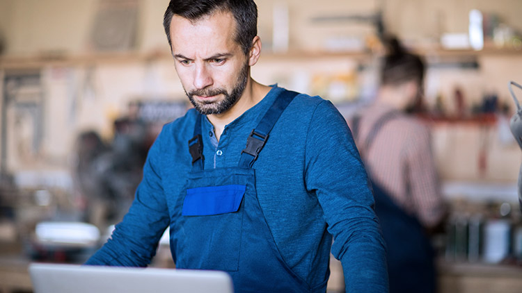 man-in-woodworking-shop-looks-at-computer